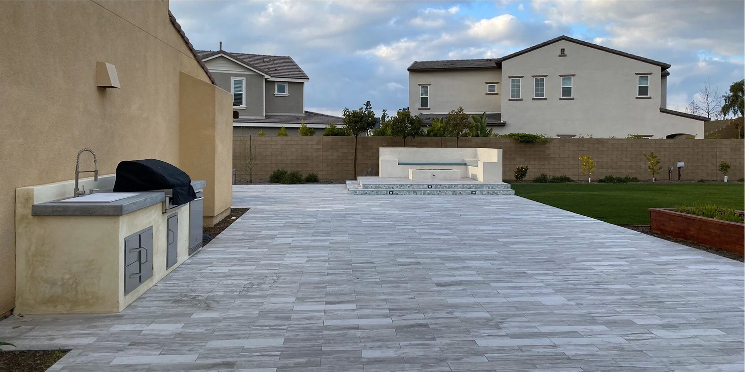After: finished paver patio with outdoor kitchen and fire feature