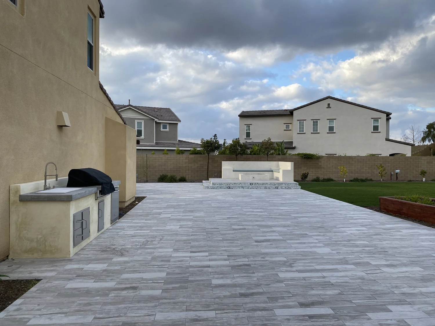 Backyard paver patio with built-in barbecue island by JBC